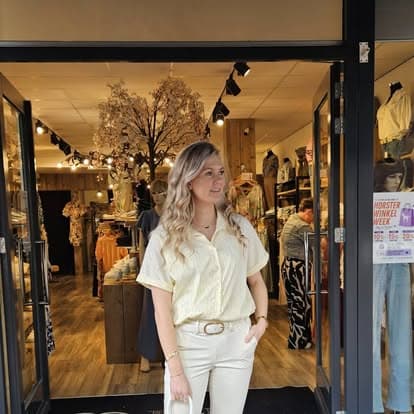 Klant in beige blouse en jeans voor de winkel