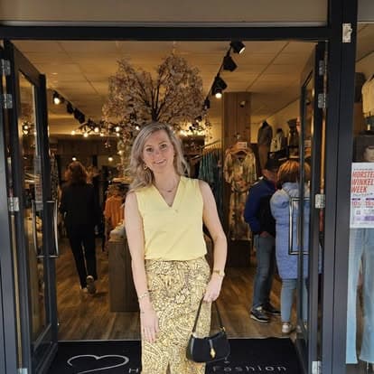 Klant in een outfit uit onze damesmode-collectie voor de winkelingang